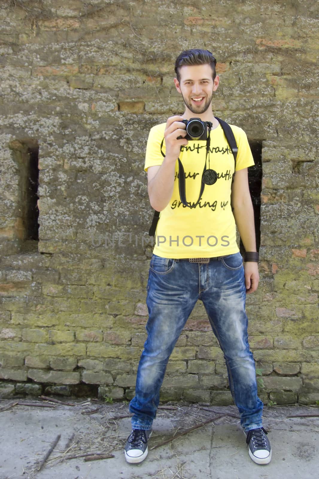 Young smiled man taking a photo in yellow t-shirt by fadeinphotography