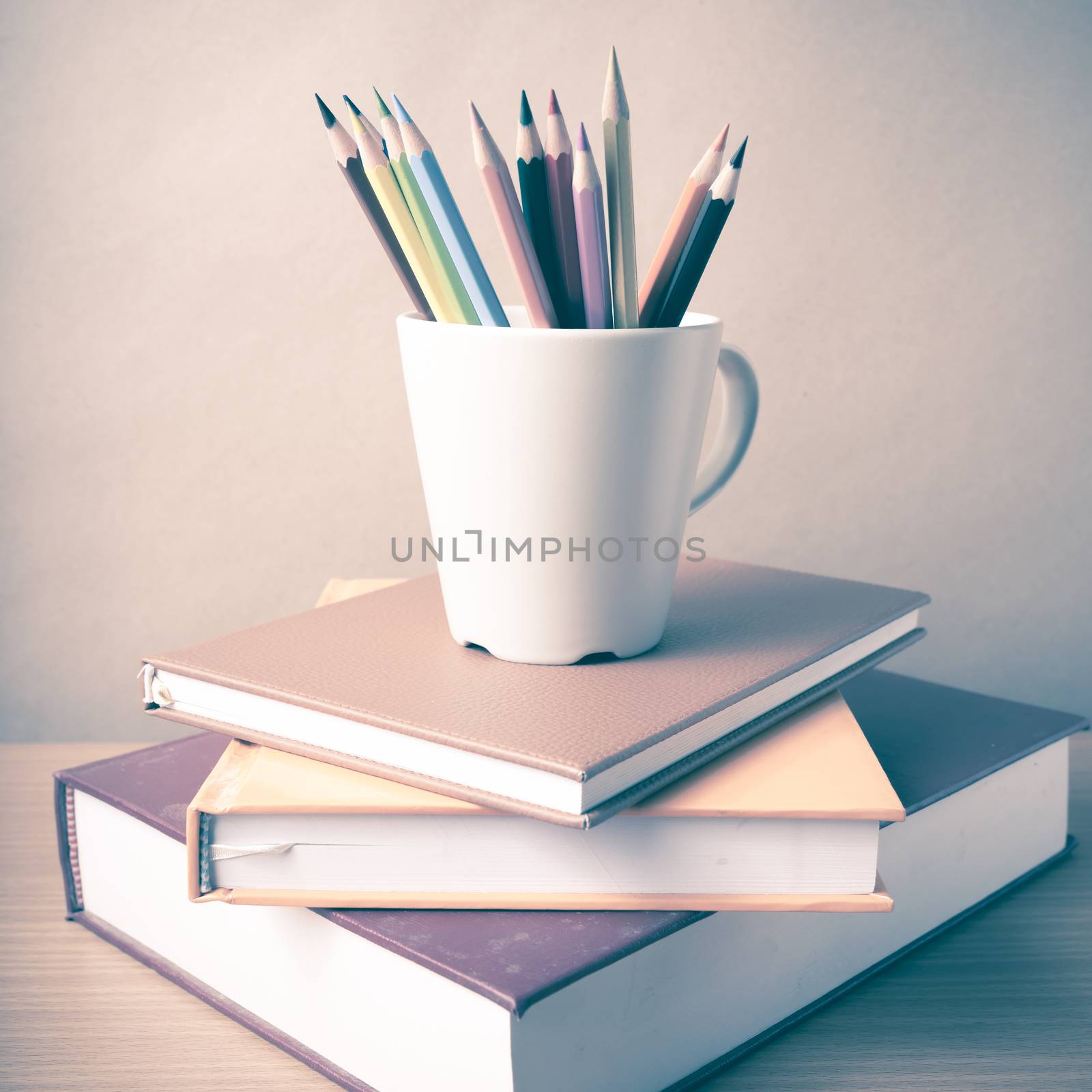 stack of book with color pencil on wood table background vintage style