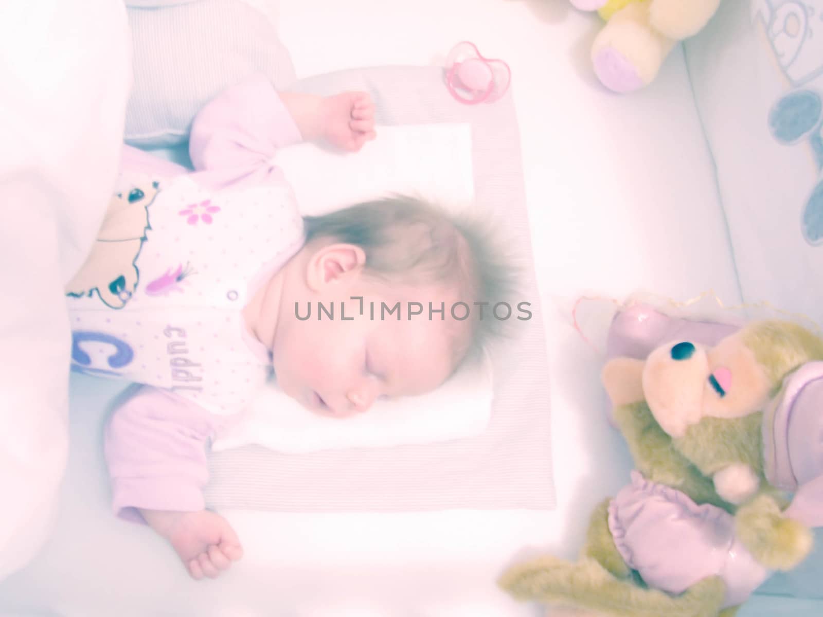 Newborn baby sleeping with toys by fadeinphotography