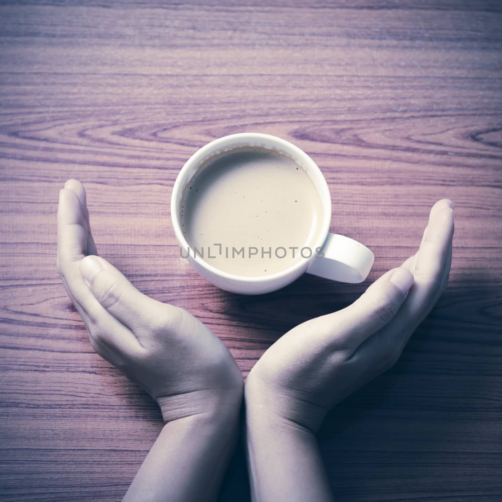 woman hand holding coffee cup on wood table background vintage style