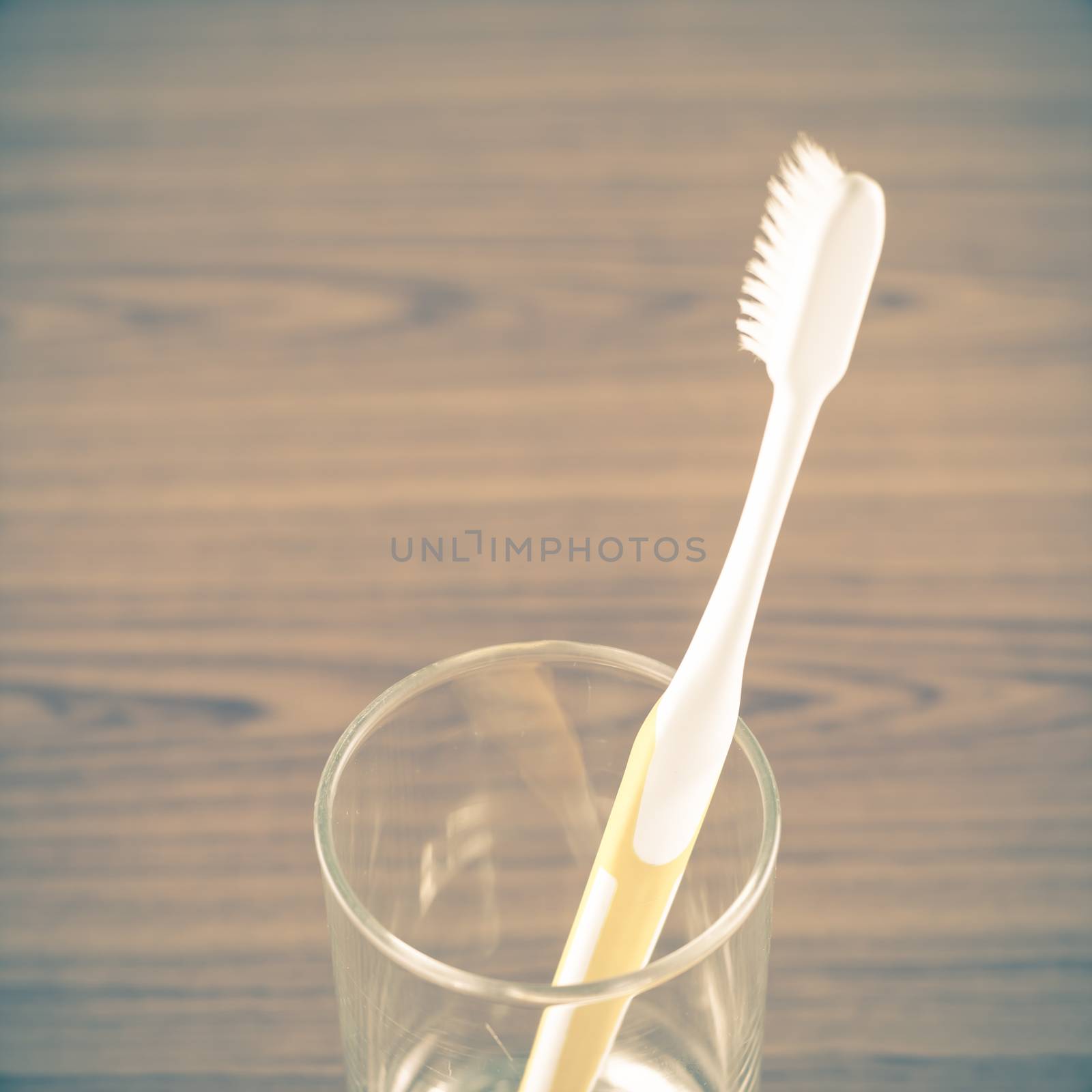 toothbrush in glass on wood background vintage style