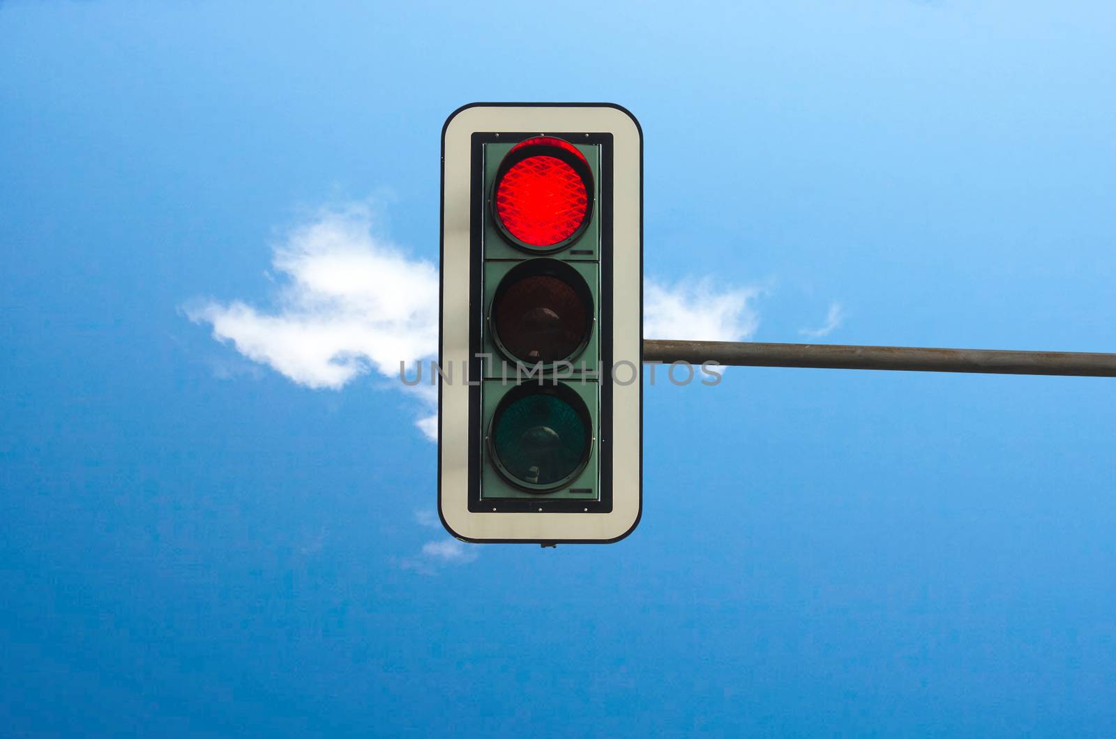 Red color on the traffic light with a beautiful blue sky in the background
