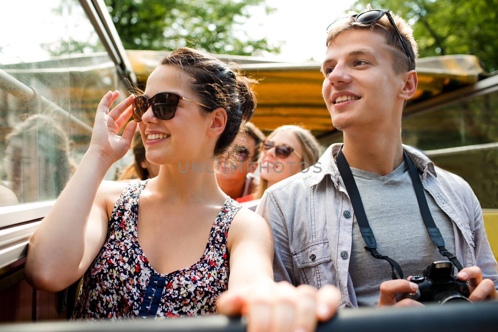 friendship, travel, vacation, summer and people concept - smiling couple with camera traveling by tour bus