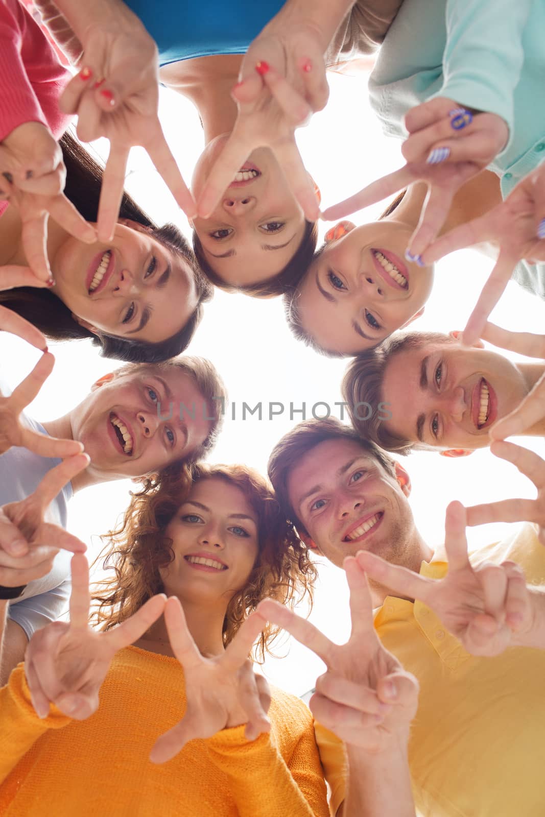 friendship, youth, gesture and people - group of smiling teenagers in circle showing victory sign