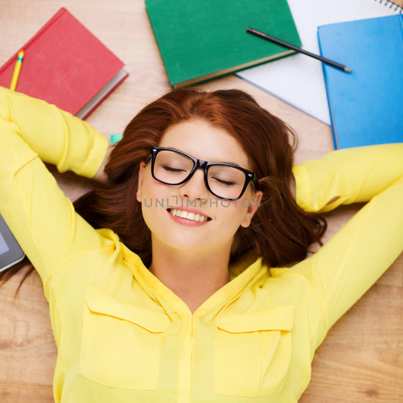 education and home concept - smiling redhead female student in eyeglasses lying on floor with closed eyes