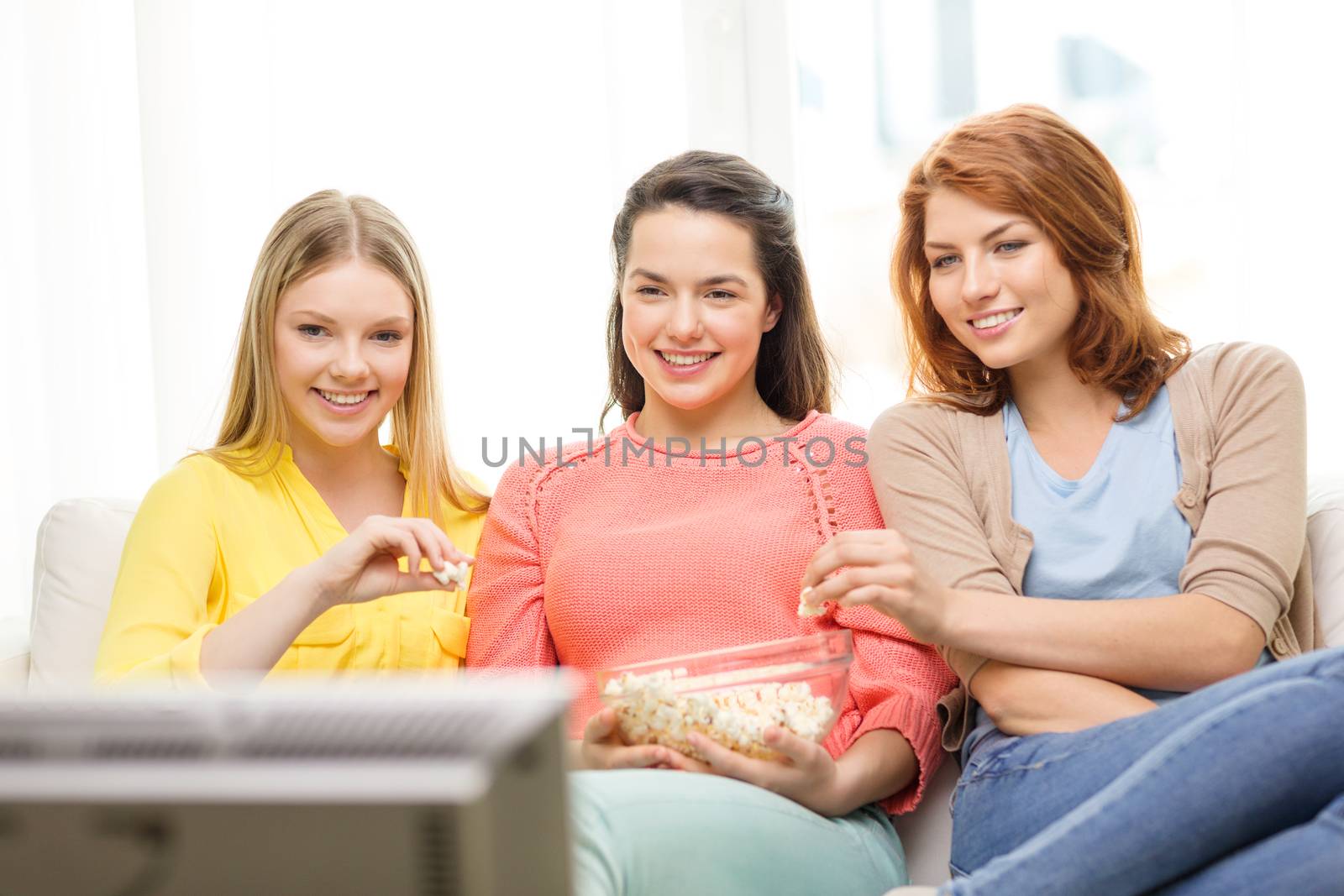 three smiling teenage girl watching tv at home by dolgachov