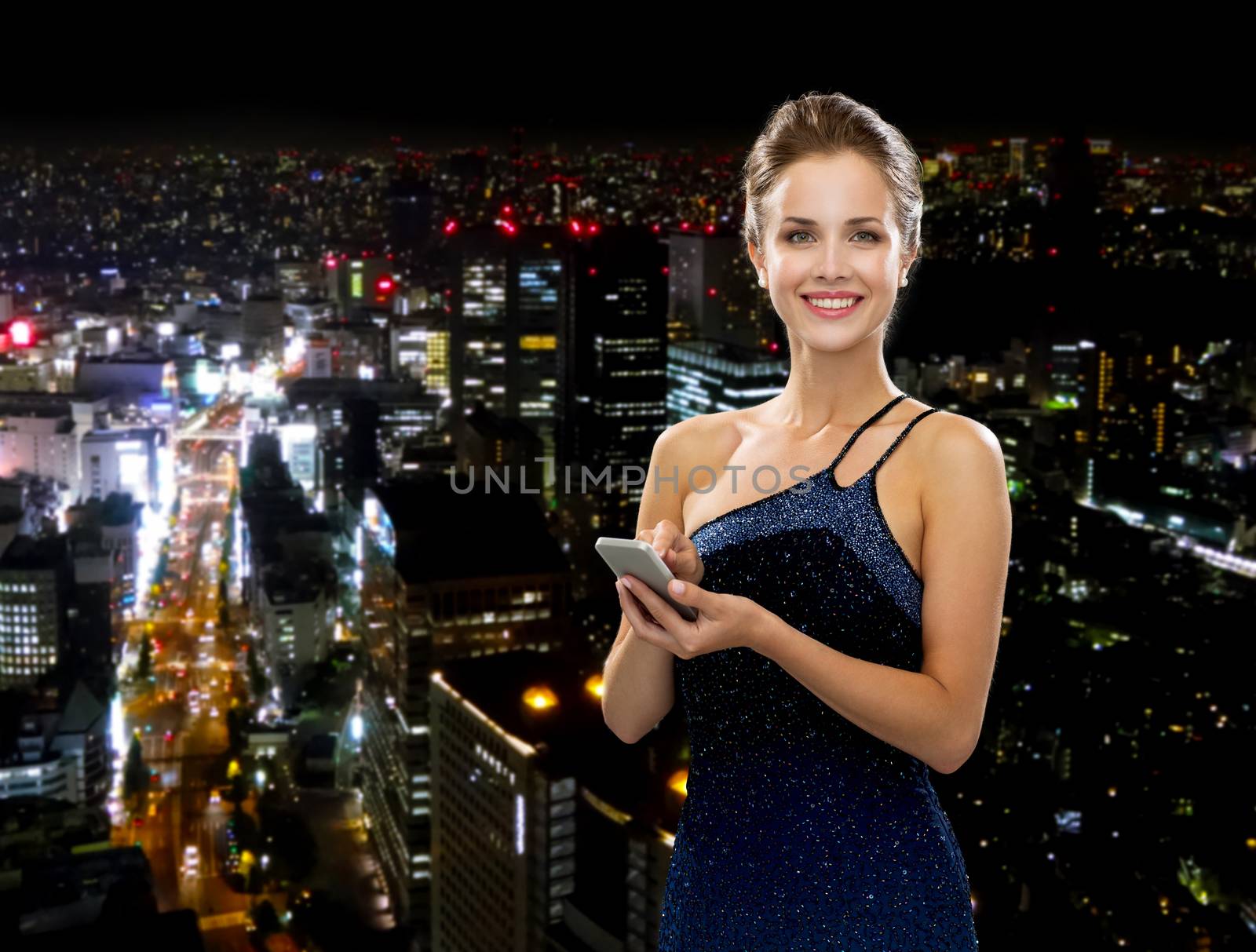 technology, communication and people concept - smiling woman in evening dress holding smartphone over night city background