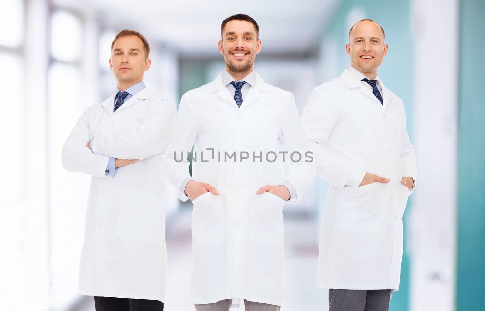 healthcare, profession, teamwork and medicine concept - smiling male doctors in white coats over hospital corridor background