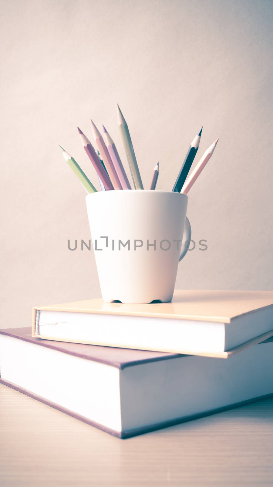 stack of book with color pencil on wood table background vintage style