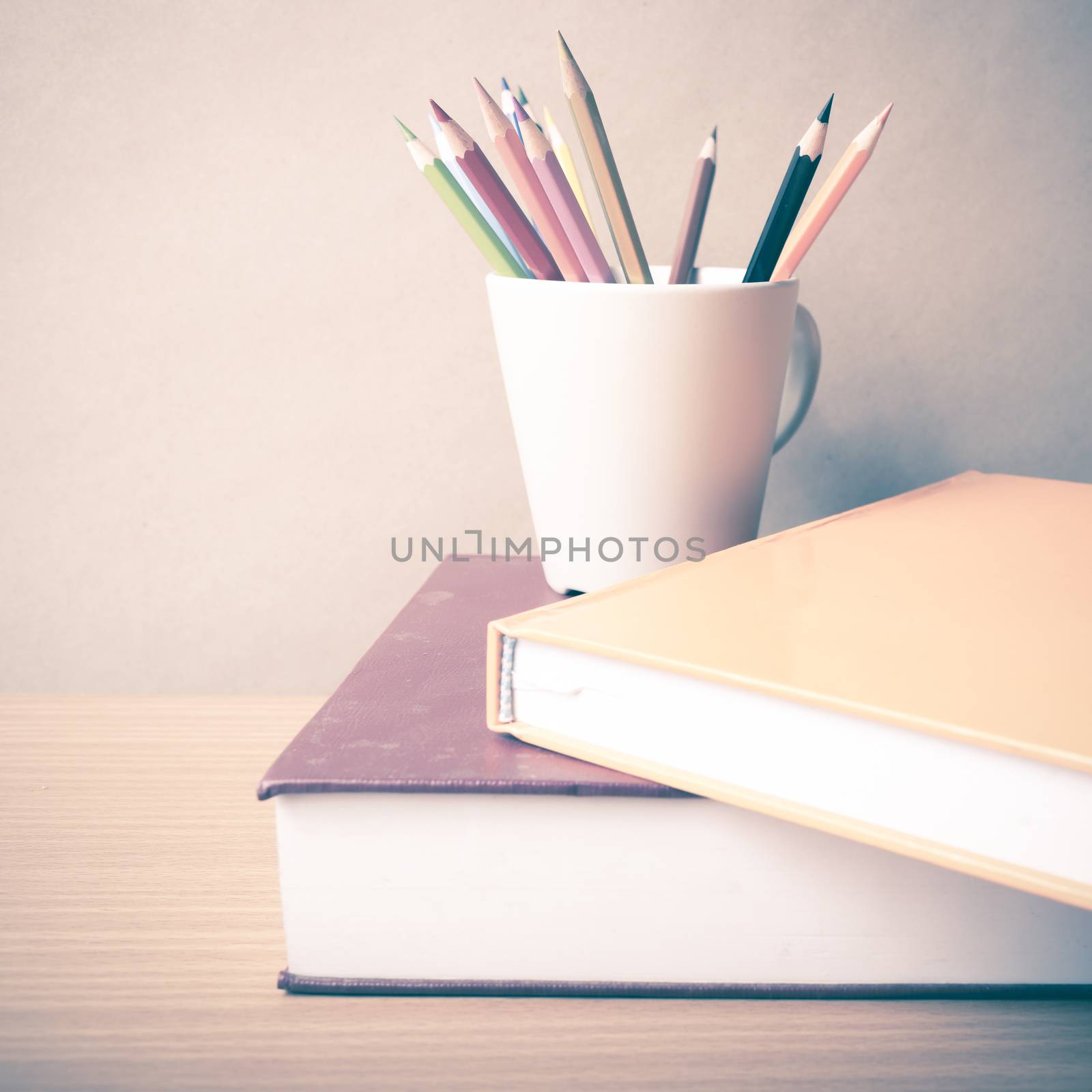 stack of book with color pencil on wood table background vintage style