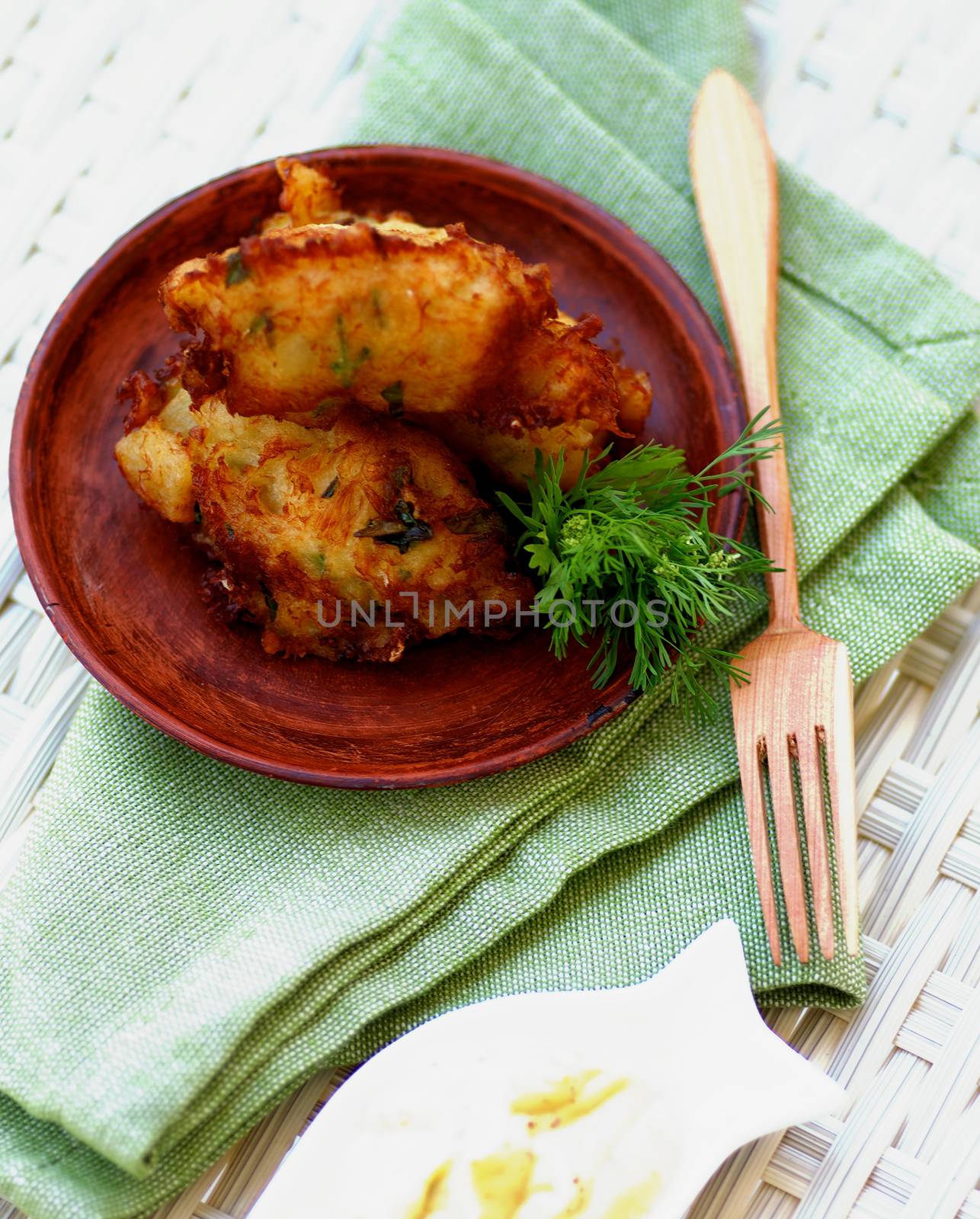 Delicious Breaded Fish Cutlets with Greens and Tartar Sauce on Brown Plate with Wooden Fork closeup on Green Napkin. Top View