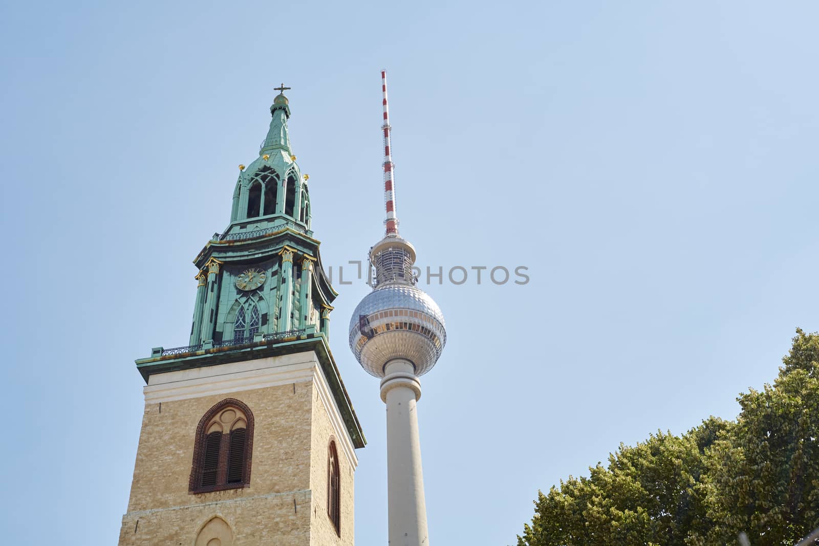 BERLIN, GERMANY - JULY 07: Low angle shot of TV tower in Alexanderplatz, with Saint Mary's Church tower in the foreground. July 07, 2015 in Berlin.