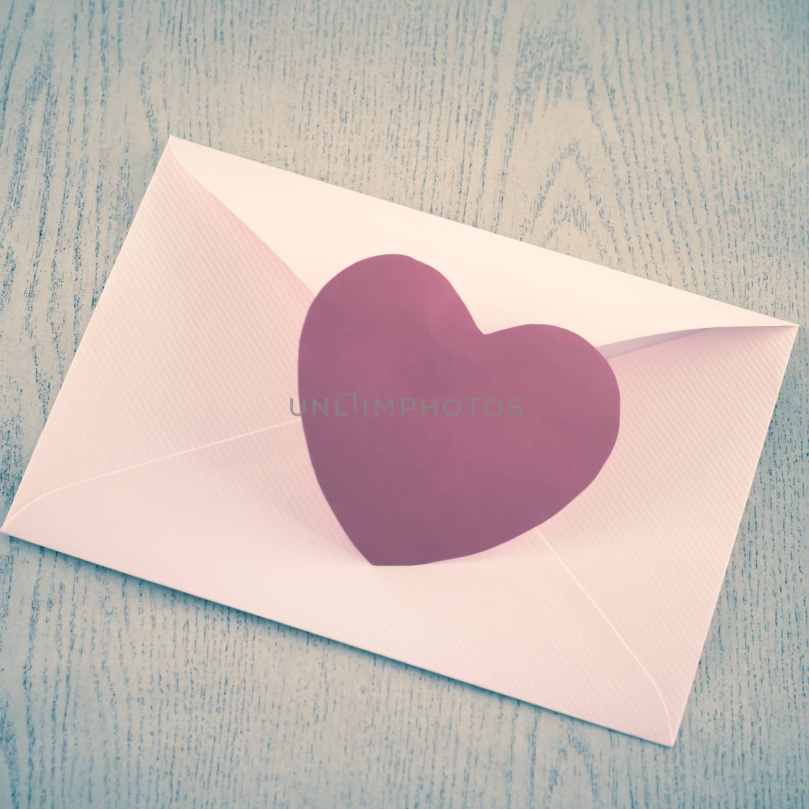 red heart with pink envelope on wooden background vintage style