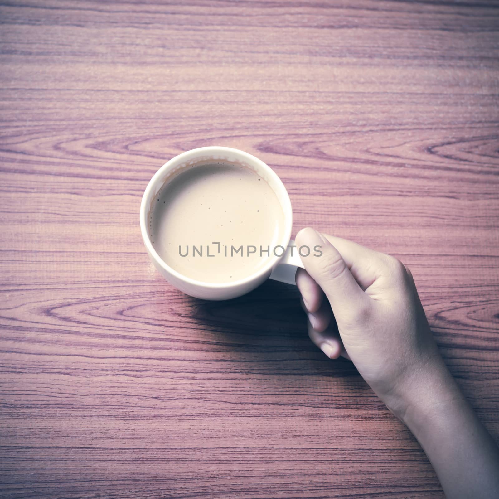 woman hand holding coffee cup on wood table background vintage style