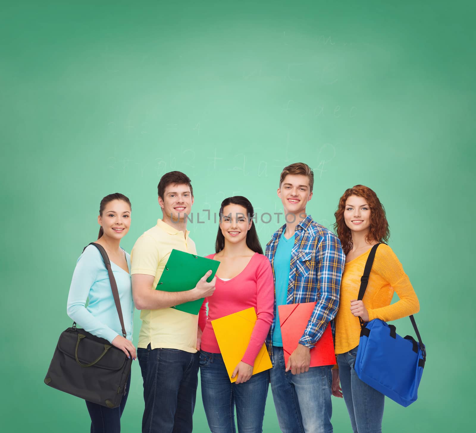 friendship, education and people concept - group of smiling teenagers with folders and school bags over green board background