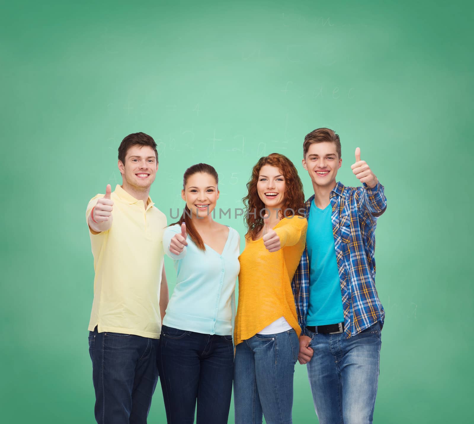 friendship, education, school and people concept - group of smiling teenagers showing thumbs up over green board background