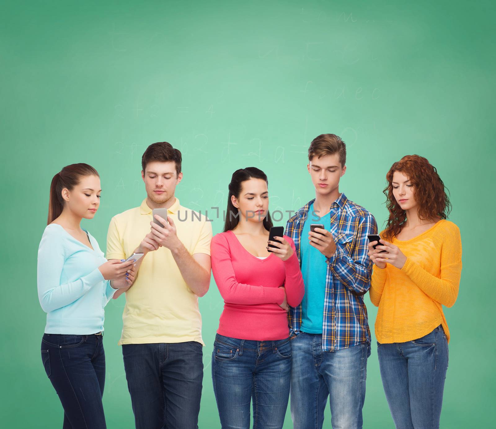friendship, technology, education, school and people concept - group of serious teenagers with smartphones over green board background