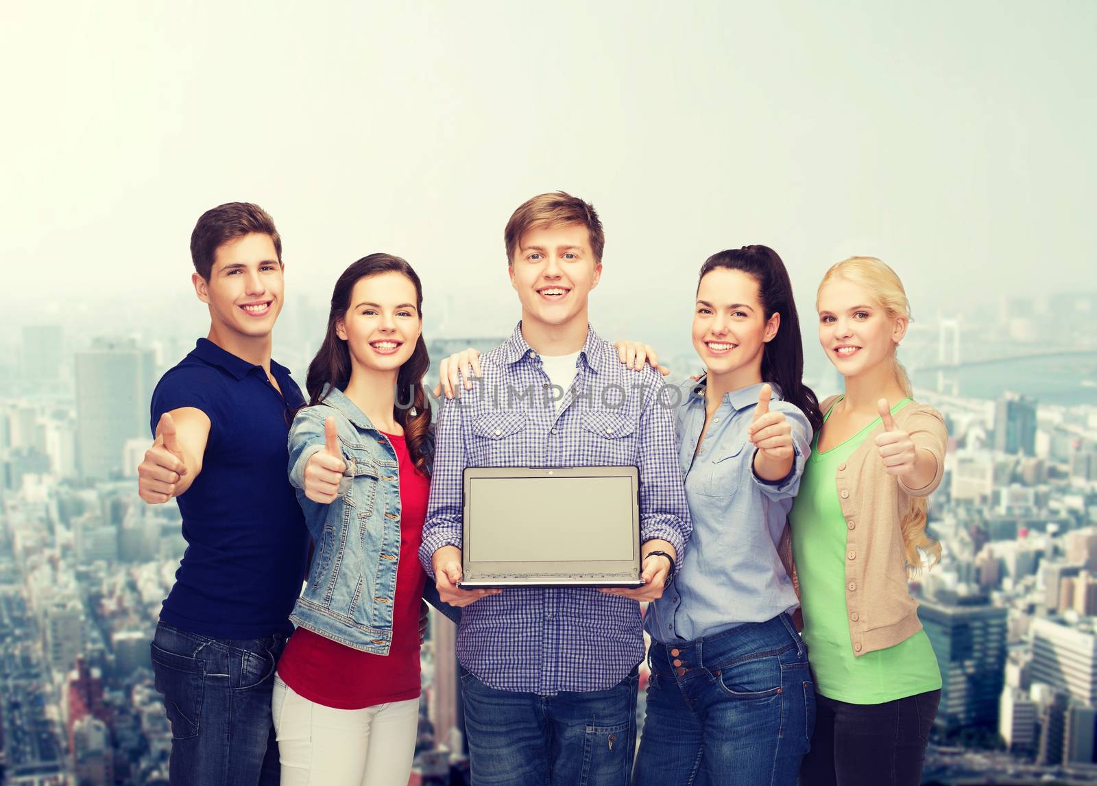 education, advertisement and new technology concept - smiling students with laptop computer blank screen showing thumbs up