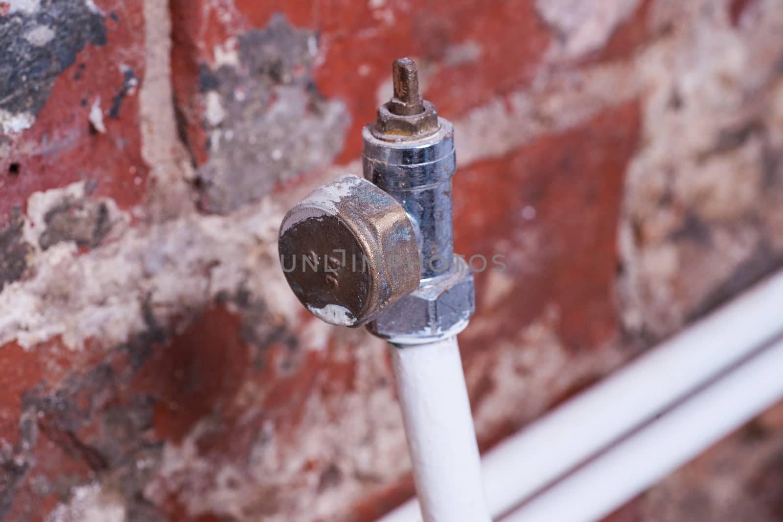 capped off radiator pipe in domestic home against a bare brick wall