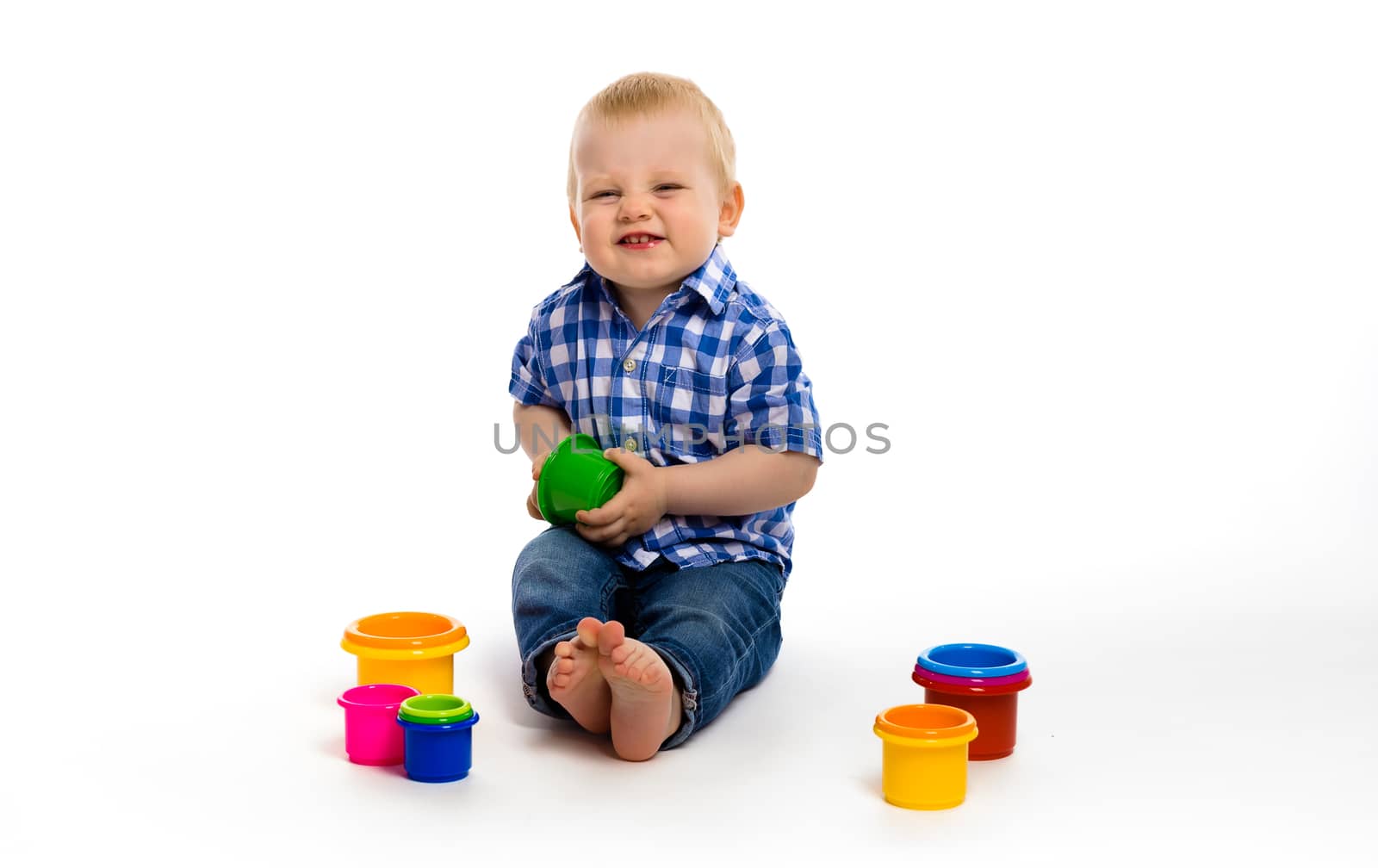 Happy baby boy in a plaid shirt with toys. studio