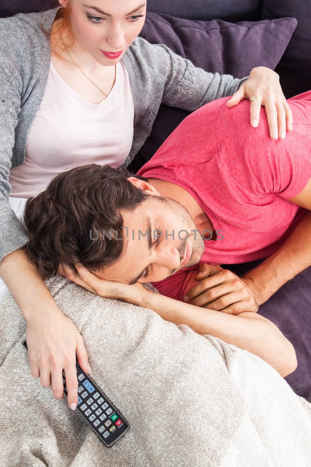 Young Couple Relaxing on the Couch In the Living Room, with Pensive Facial Expressions, While Boyfriend is Lying on the Lap of her Girlfriend.