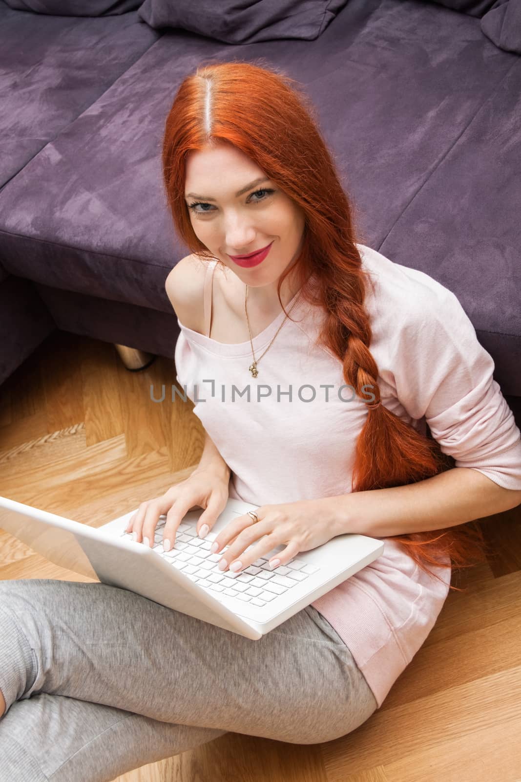 Pretty Young Woman Using her Laptop Computer In the Living Room with Feet on the Table and Showing Serious Face.