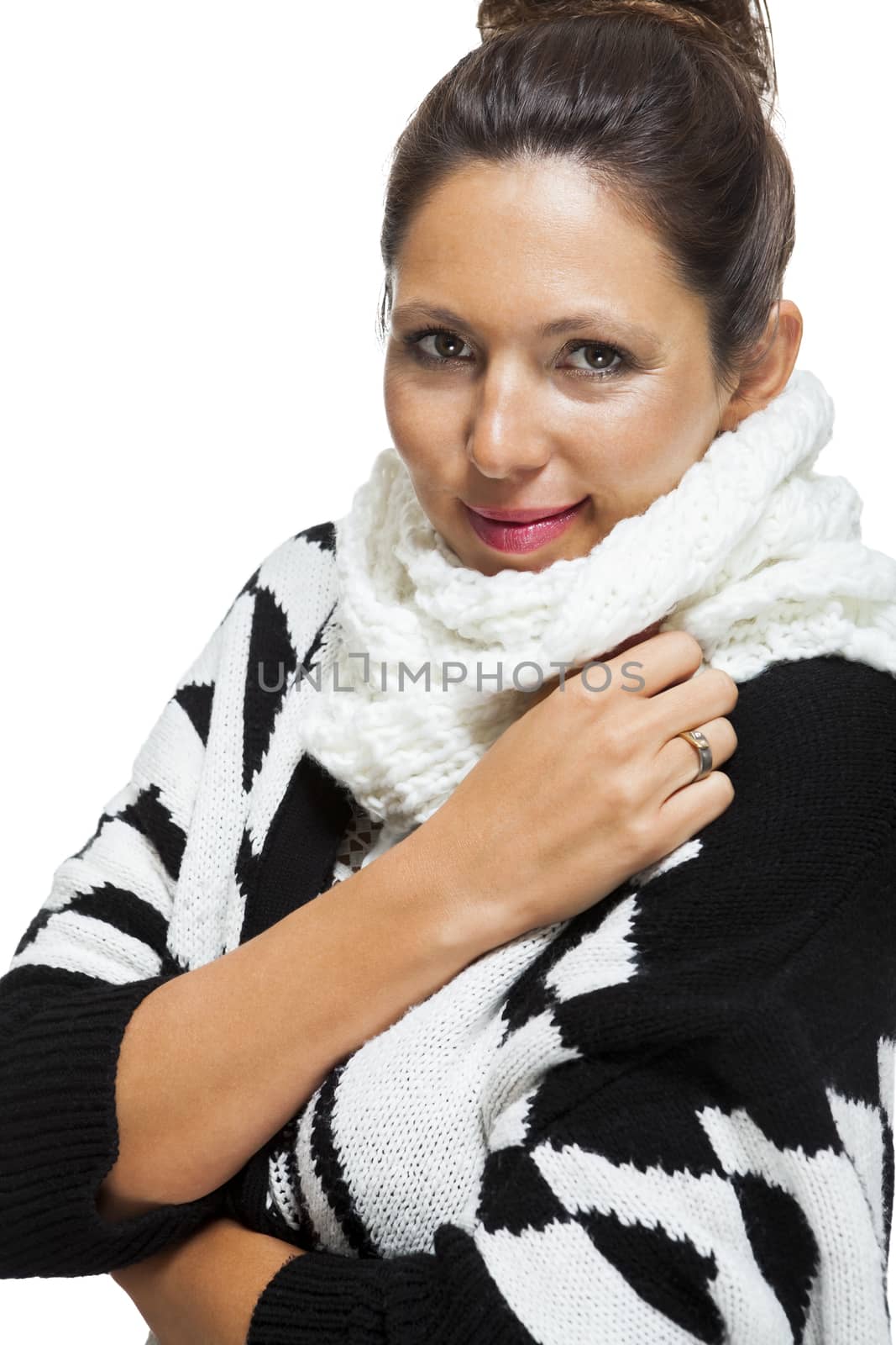 Attractive elegant woman in winter fashion snuggling down into her white scarf and black and white jumper to ward off the cold winter weather, on white