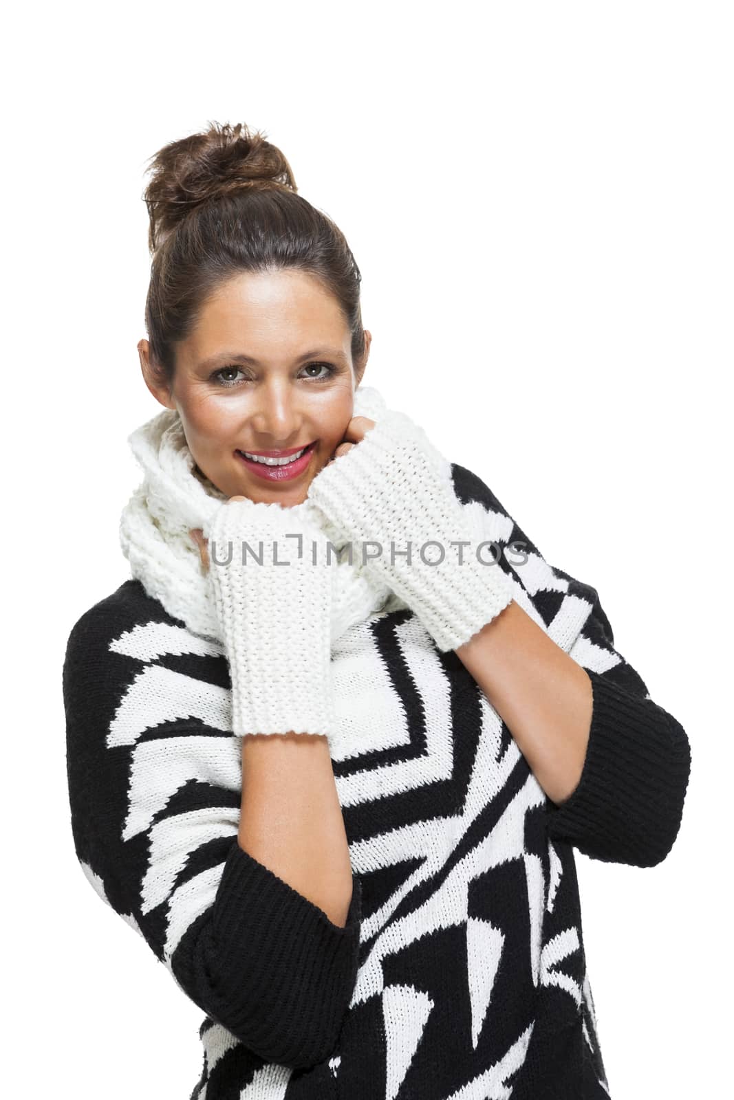 Attractive elegant woman in winter fashion snuggling down into her white scarf and black and white jumper to ward off the cold winter weather, on white