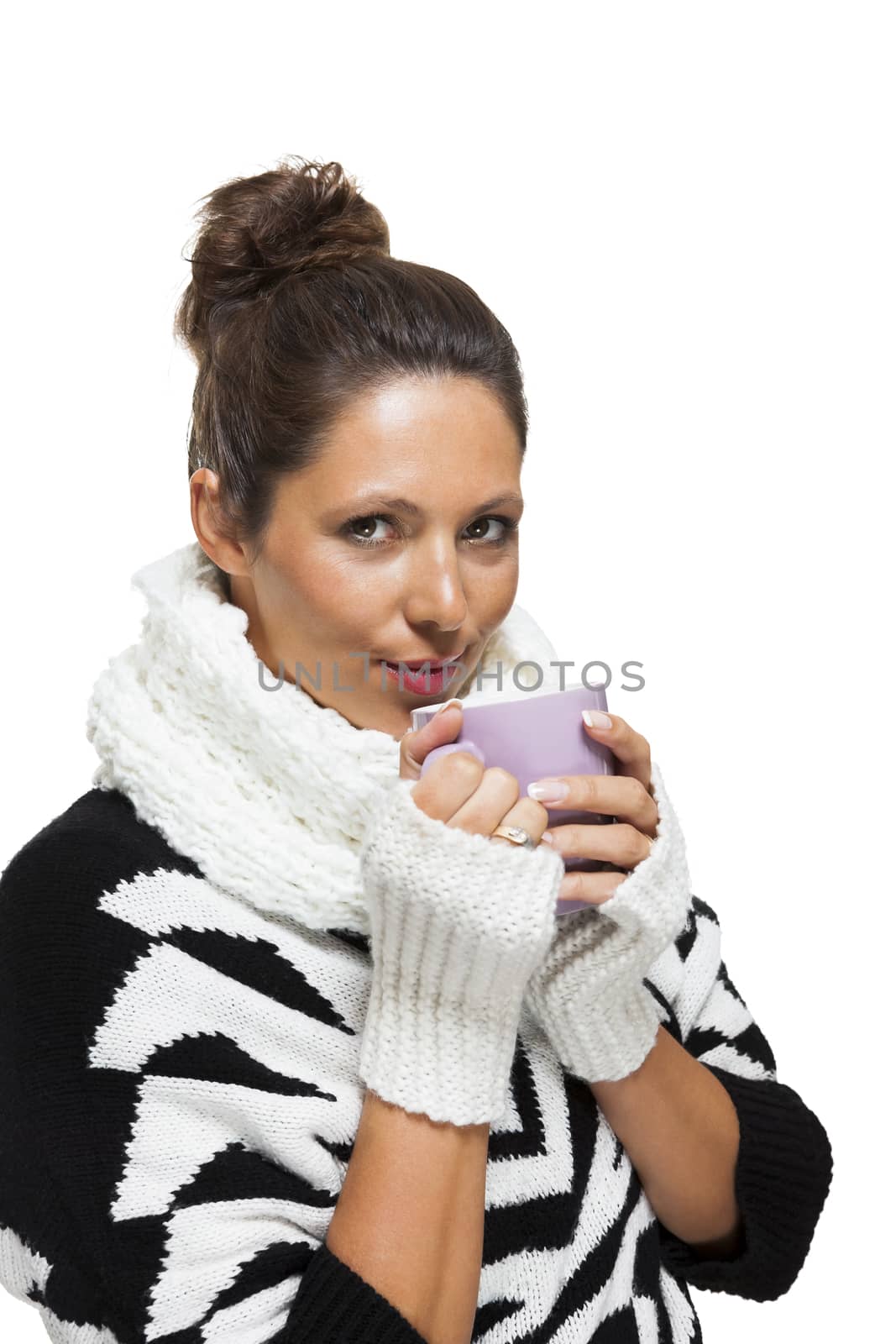 Cold attractive stylish woman in an elegant black and white winter outfit clasping a mug of hot coffee in her hands while savoring the aroma with a look of anticipation