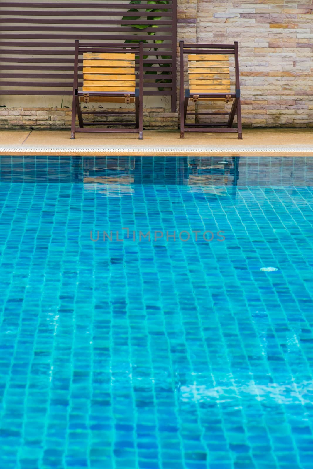 Chair on ground beside swimming pool day time with nobody