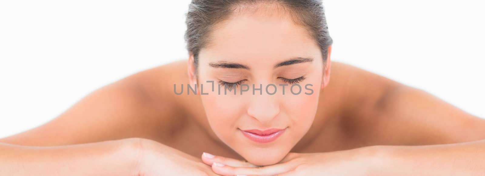 Smiling pretty brunette on massage table with white backgroung 