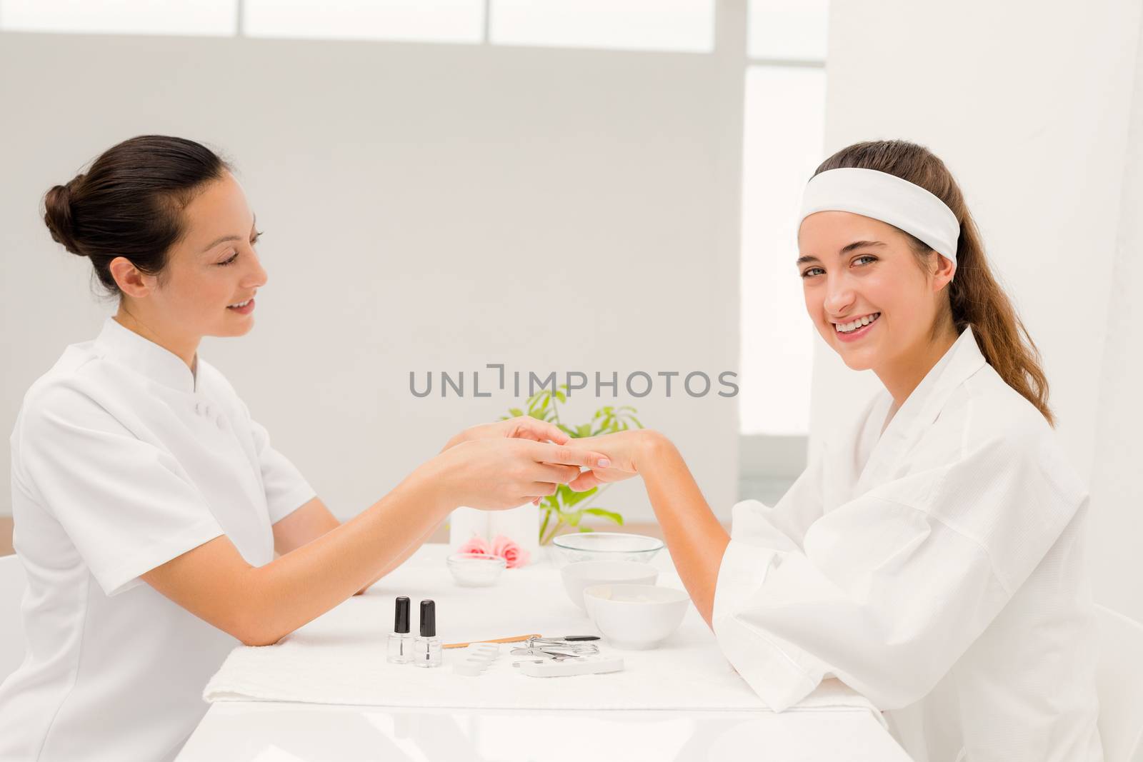 Close up of beautician applying nail varnish to female clients nails at spa beauty salon