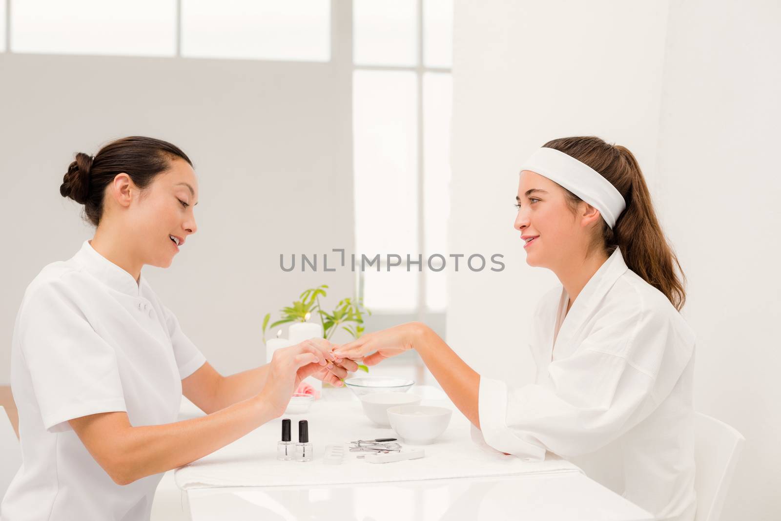 Beautiful woman with beautician applying nail varnish to female clients nails by Wavebreakmedia