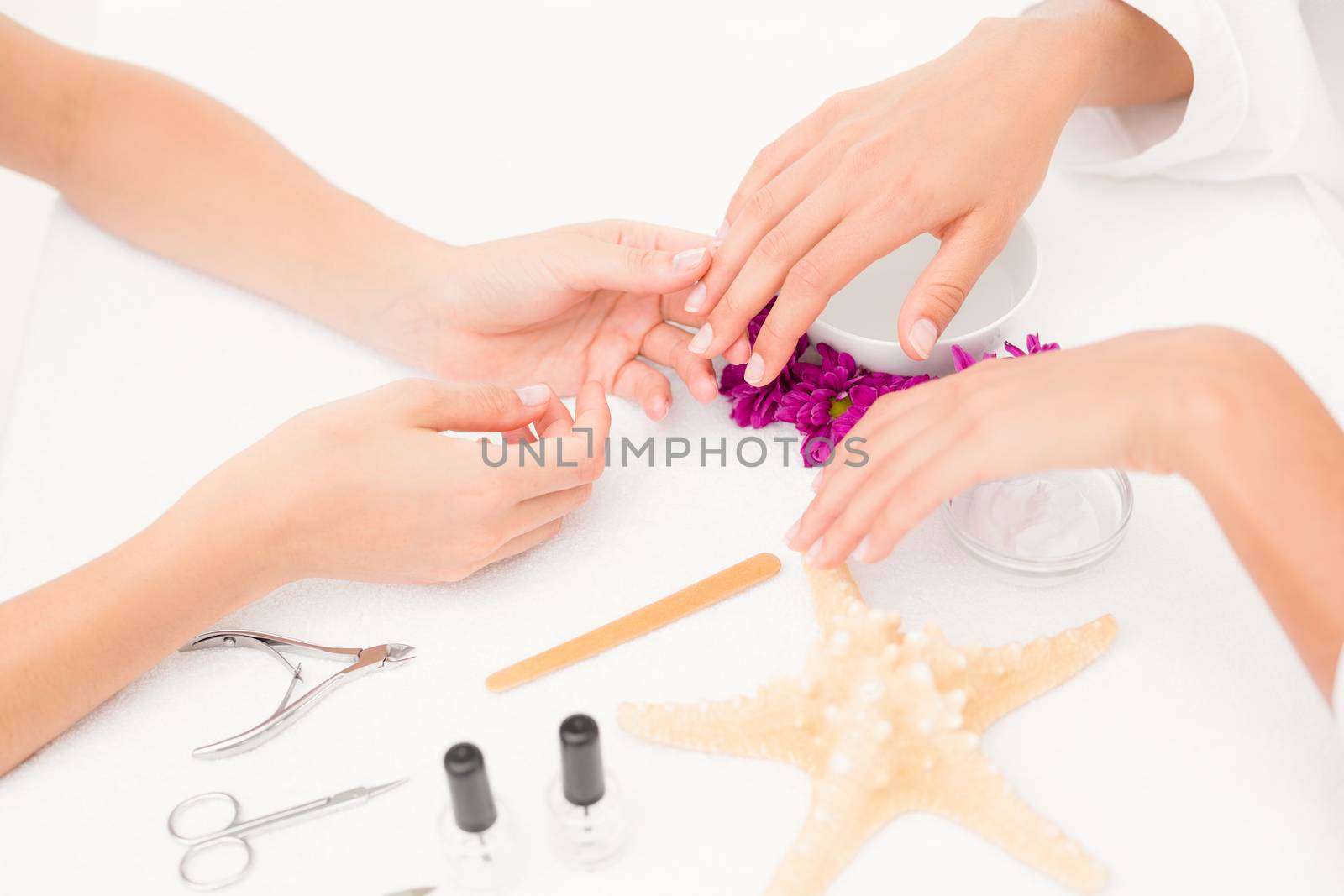 Close up of beautician filing female clients nails at spa beauty salon