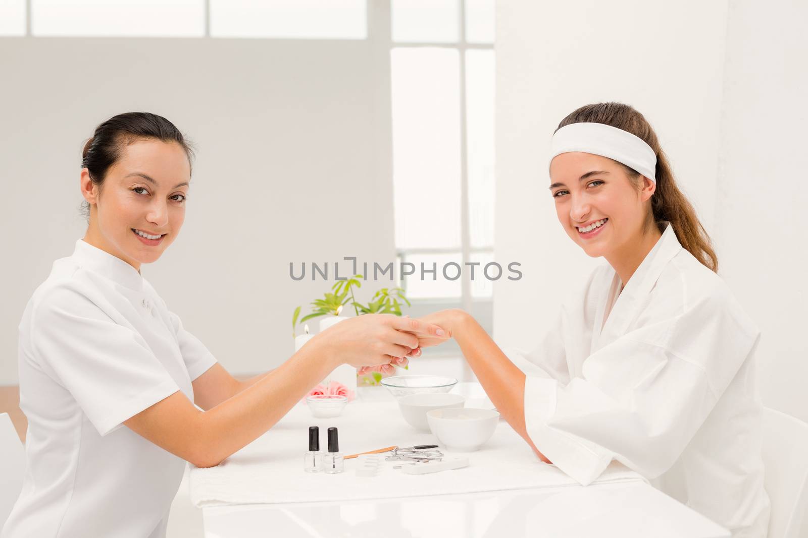 Close up of beautician applying nail varnish to female clients nails at spa beauty salon