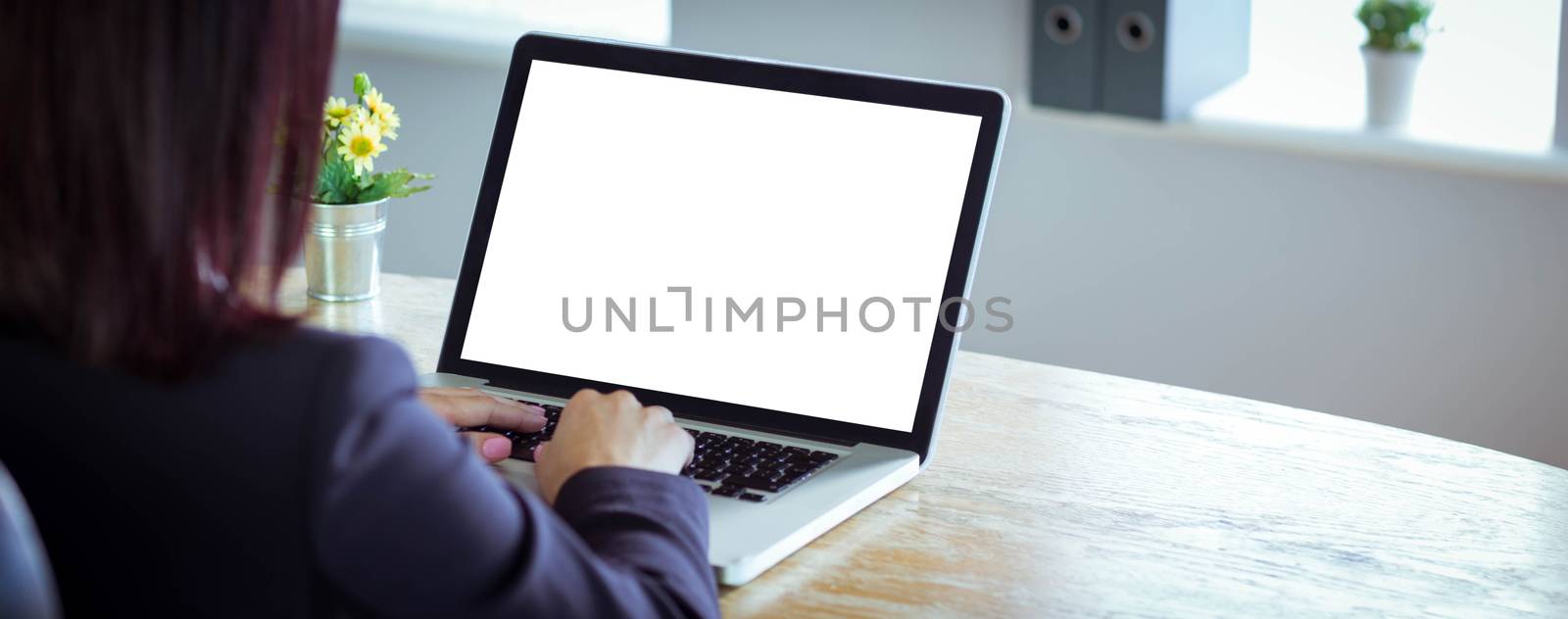 Businesswoman working at her desk on laptop in her office