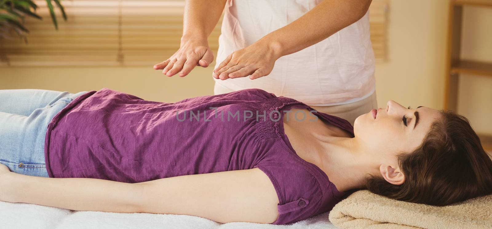 Young woman having a reiki treatment in therapy room