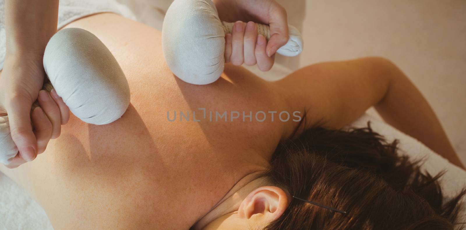 Young woman getting herbal compress massage by Wavebreakmedia