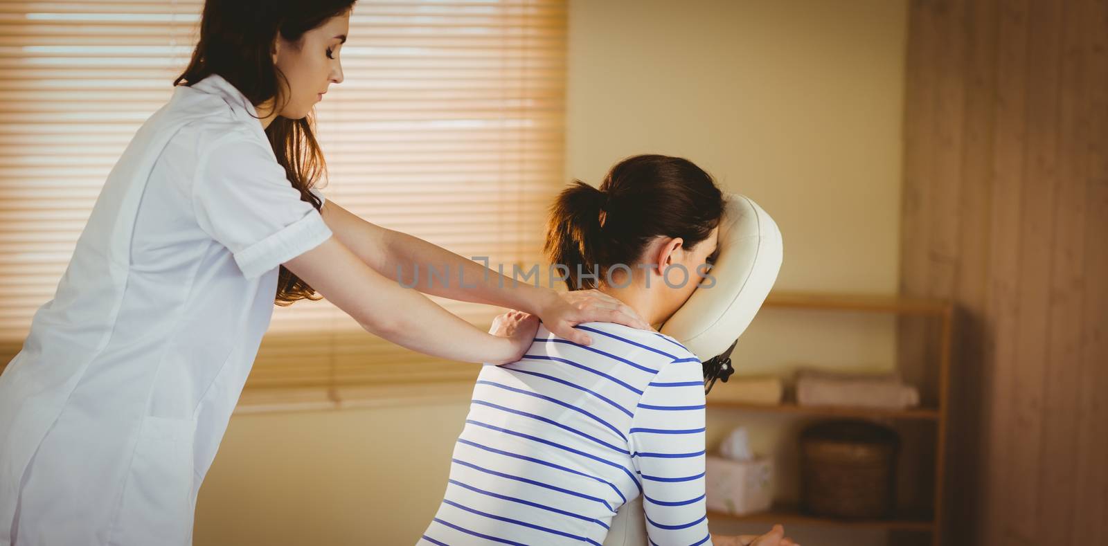 Young woman getting massage in chair in therapy room