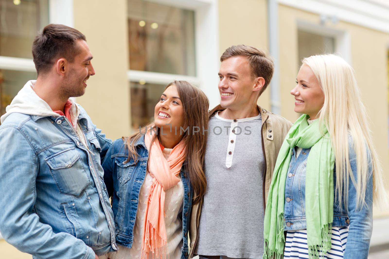 group of smiling friends walking in the city by dolgachov