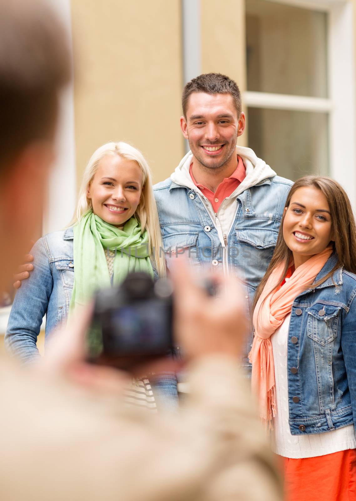 travel, vacation, technology and friendship concept - guy picturing group of friends in city