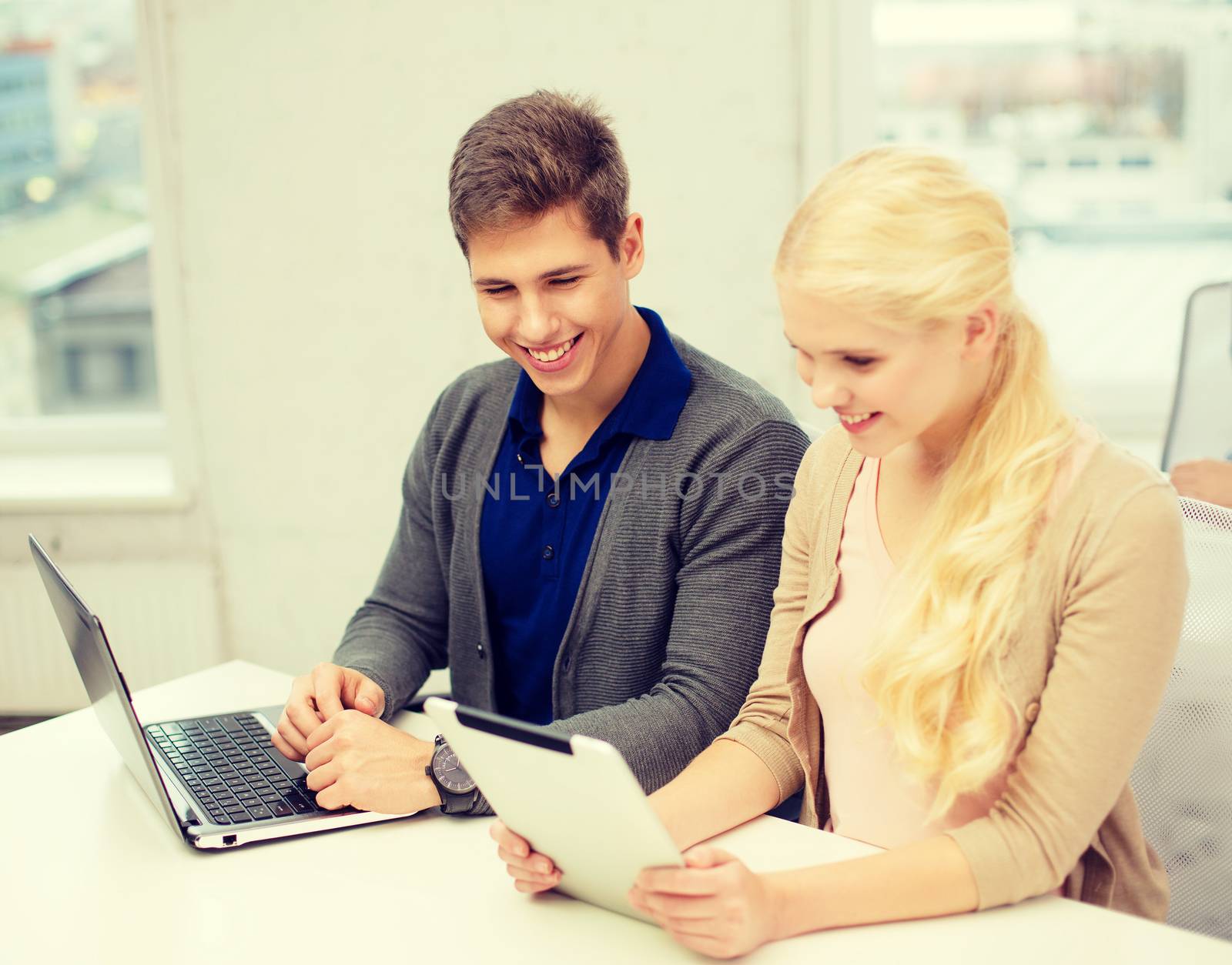 school, education, technology and internet concept - two teens with laptop and tablet pc at school