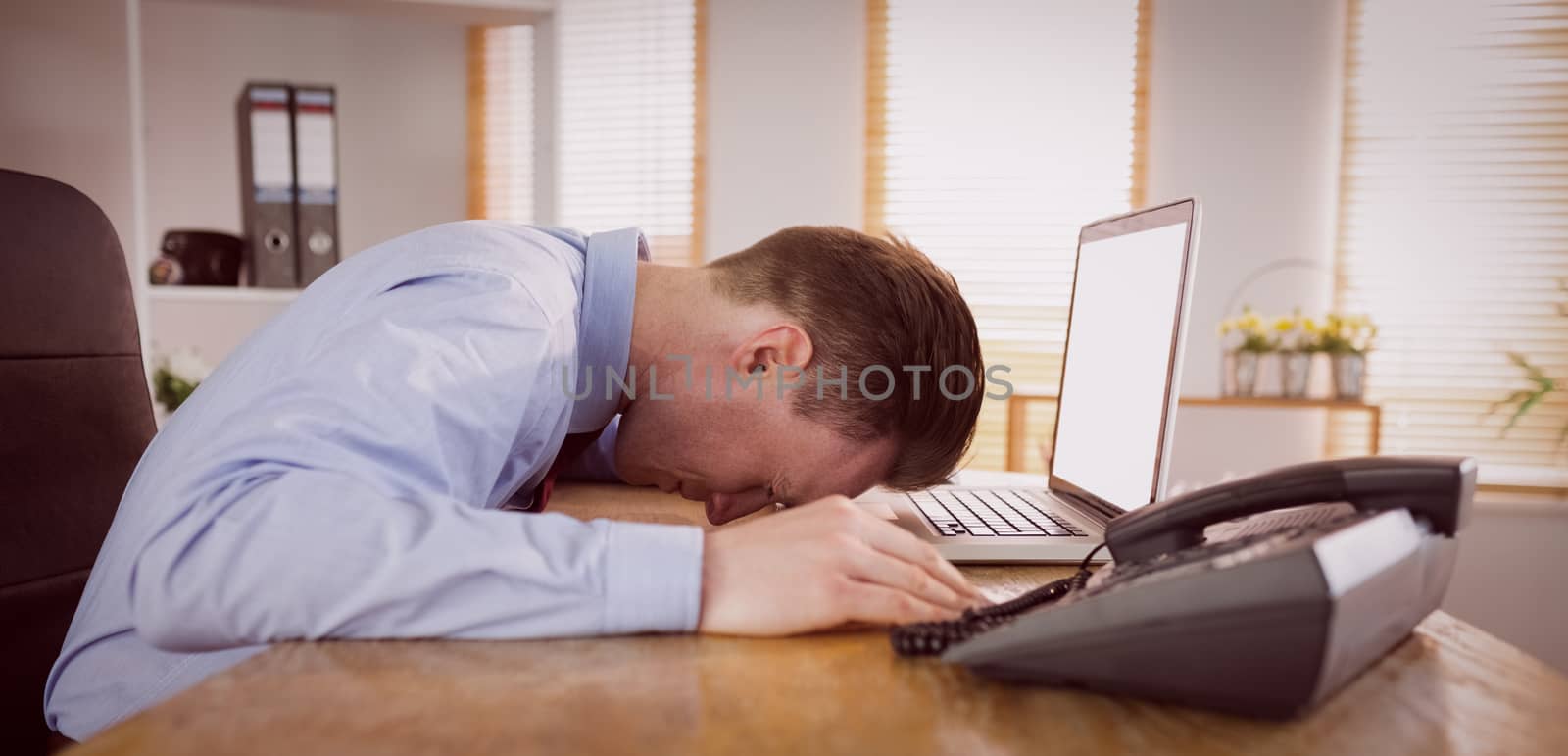 Stressed businessman with head on laptop in his office