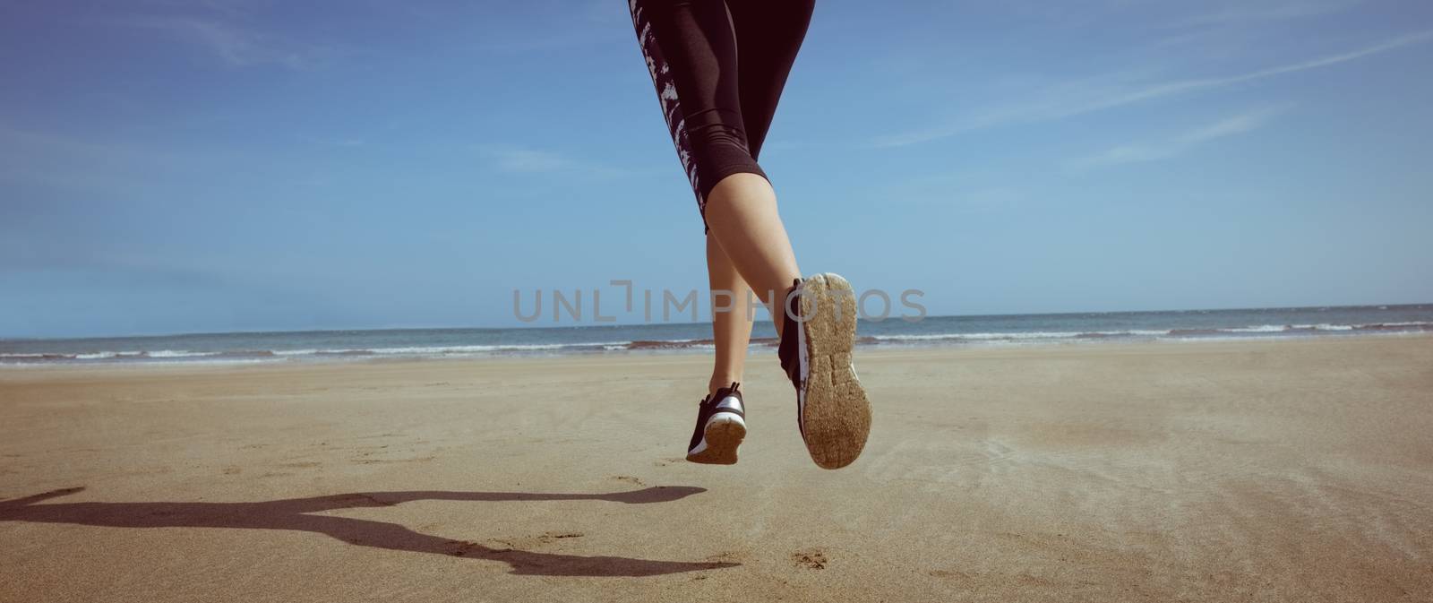 Fit woman jogging on the sand at the beach