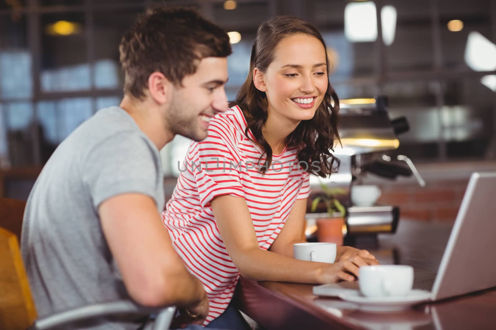 Smiling friends using laptop and having coffee together by Wavebreakmedia
