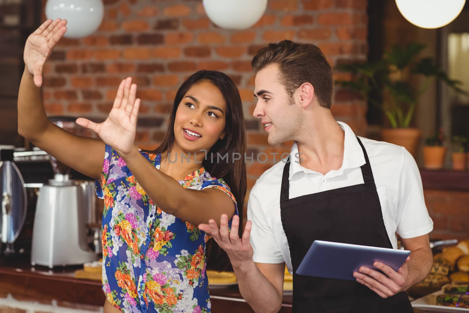 Pretty customer explaining to waiter at coffee shop