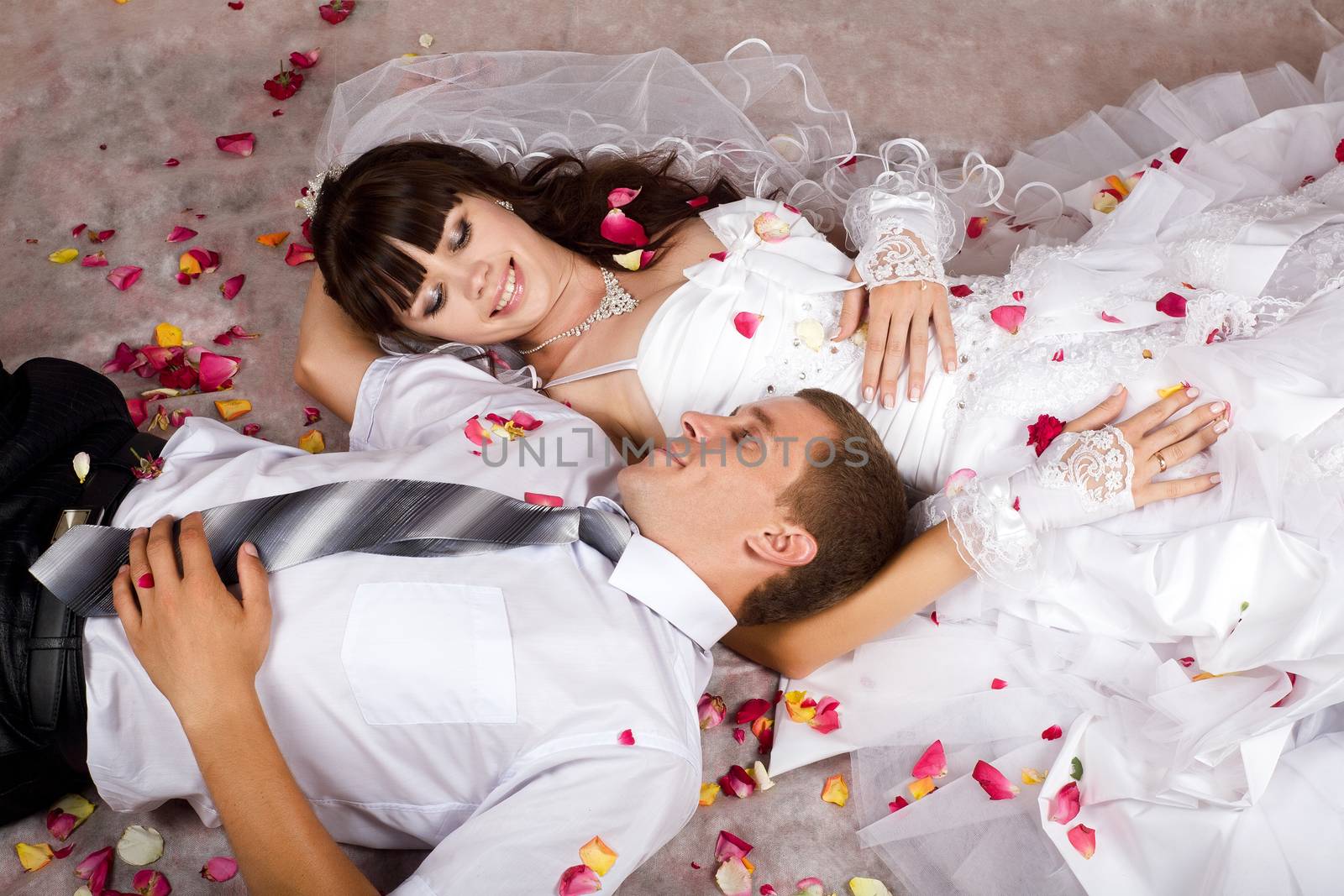 The bride and groom in wedding clothes, showering lepestami roses, lie on your back and look at each other's eyes