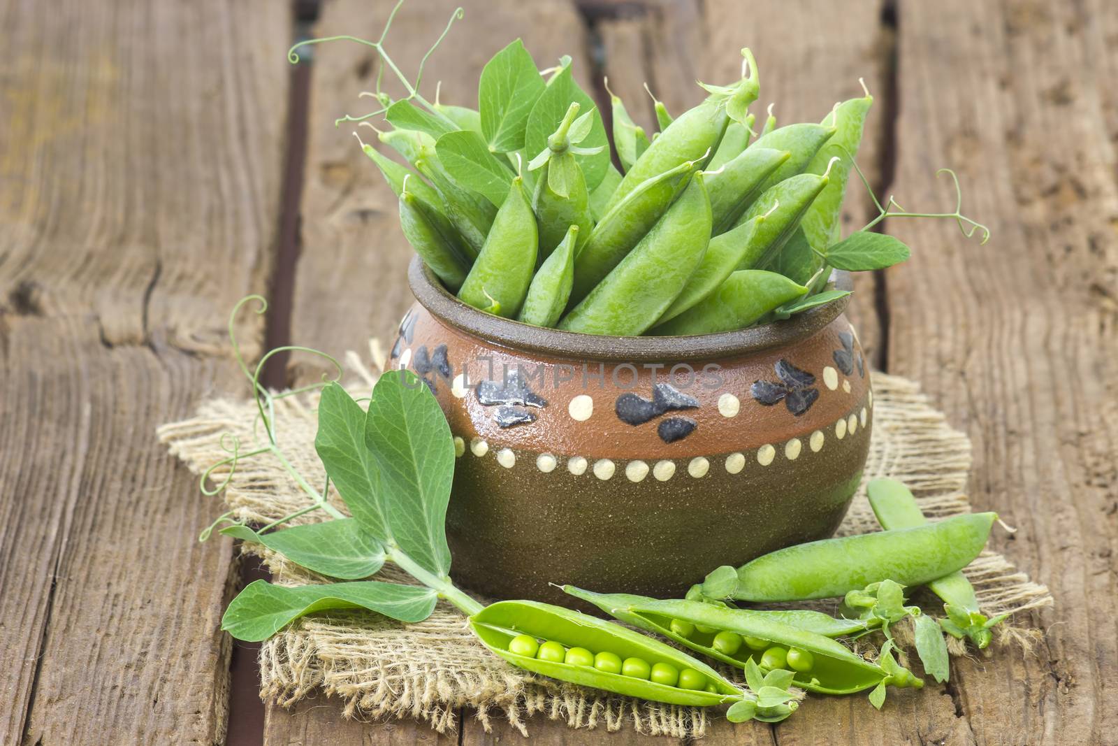 pot full of green peas on wooden background