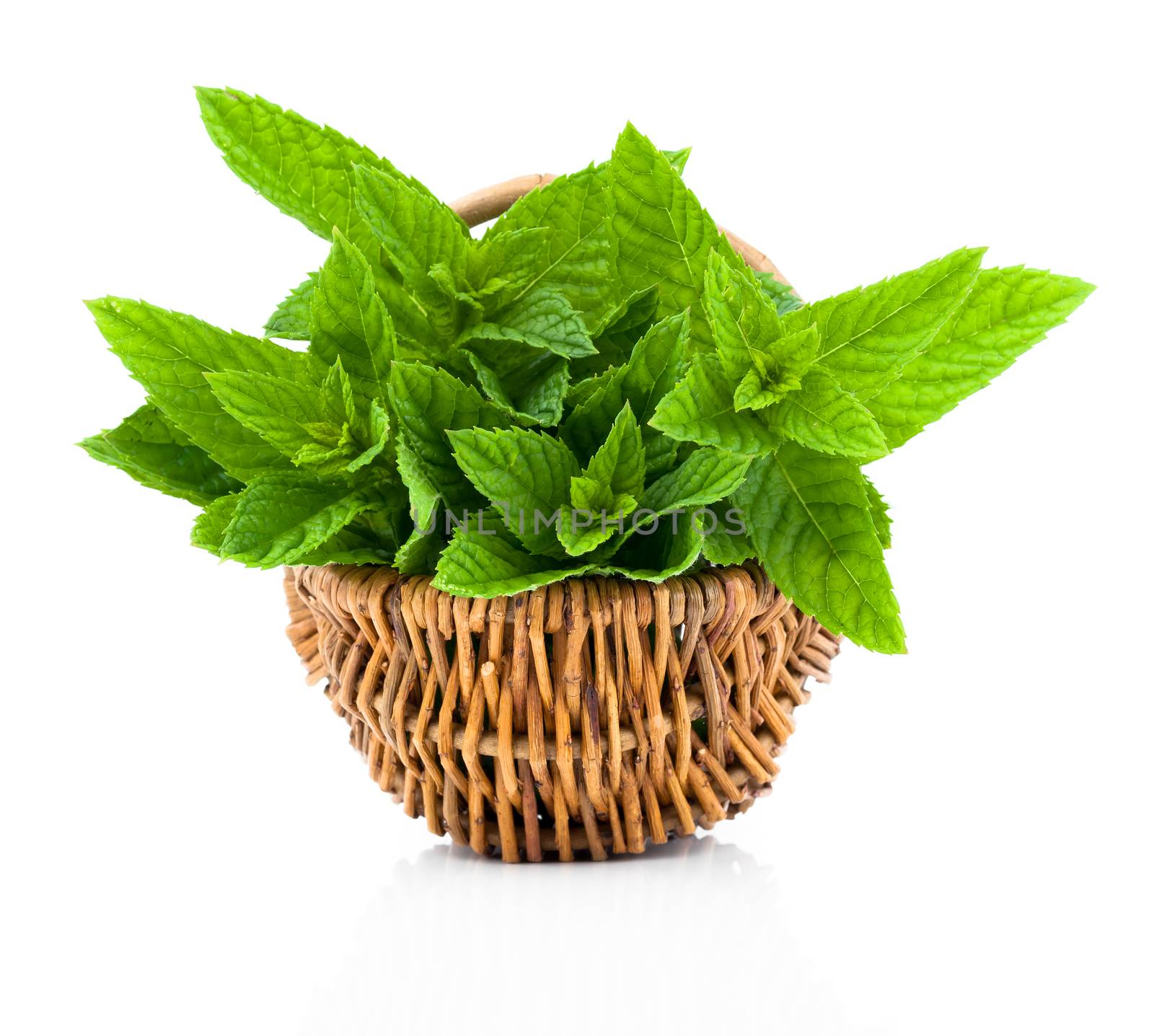 Bundle of fresh spearmint in a wicker basket, on a white backgro by motorolka