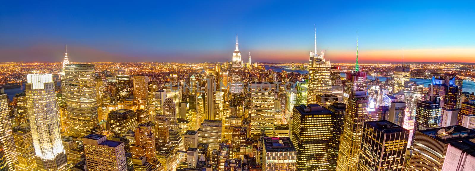 New York City. Manhattan downtown skyline with illuminated Empire State Building and skyscrapers at dusk seen from observation deck. Horisontal panoramic composition.